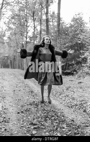 60er Jahre Mode-Modell mit Pelzmantel in Wald laufen Stockfoto