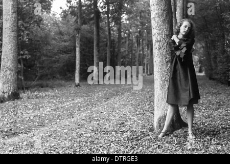 60er Jahre Mode Modell mit schwarzen Mantel posiert im Wald Stockfoto