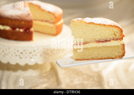 Ein Stück von Victoria Biskuit mit geschnittenen Kuchen im Hintergrund Stockfoto