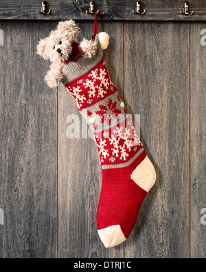 Weihnachts-Strumpf am Haken hängend gefüllt mit Teddybär Stockfoto