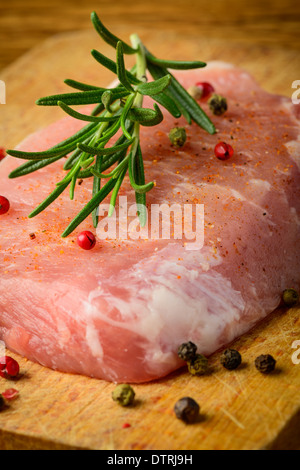 Nahaufnahme von rohem Fleisch Schweinesteak mit Rosmarin und Pfeffer Stockfoto