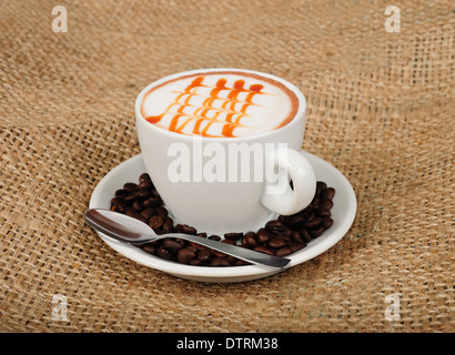 Cappuccino mit Kaffeebohnen und Teelöffel Stockfoto