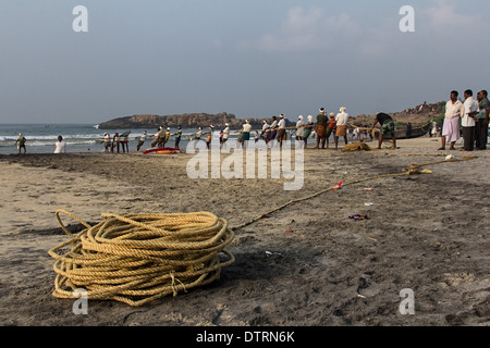 Fischer ziehen im Fischernetz im Leuchtturm Strand von Kovalam, Kerala, Indien Stockfoto