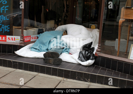 Ein Obdachloser abgebildet, schlafen in einem Kleidung Shop Eingang im Zentrum von Brighton, East Sussex, UK. Stockfoto