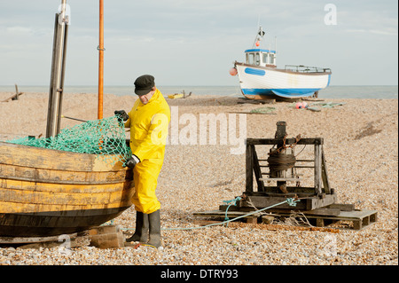 Fischer in gelben Regenschutz Anpassung der Netze auf seinem Fischerboot. Stockfoto