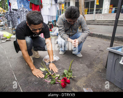Bangkok, Thailand. 24. Februar 2014. Trauernde lassen Sie Blumen und beten an der Stelle, wo drei Menschen in einem Granatenanschlag auf Anti-Regierungs-Demonstranten im Stadtteil Ratchaprasong in Bangkok getötet wurden. Mindestens vier Personen, drei Kinder, starben in politischer Gewalt über das Wochenende in Thailand. Eine in der Provinz Trat, in der Nähe der kambodschanischen Grenze und drei in Bangkok an der Ratchaprasong-Protest-Website. Am Standort Ratchaprasong wurde eine Granate in eine Menschenmenge, die Tötung eines Kindes und eines Erwachsenen gefeuert. Bildnachweis: ZUMA Press, Inc./Alamy Live-Nachrichten Stockfoto