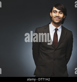 Hübscher junger Mann aussehende Weg lächelnd auf schwarzem Hintergrund. Männliche Model Business-Anzug Exemplar zu betrachten. Stockfoto