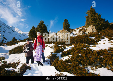 Familie (Mutter mit zwei Kindern) machen Sie einen Spaziergang am Berghang Winter (Big Almaty-See, Kasachstan) Stockfoto