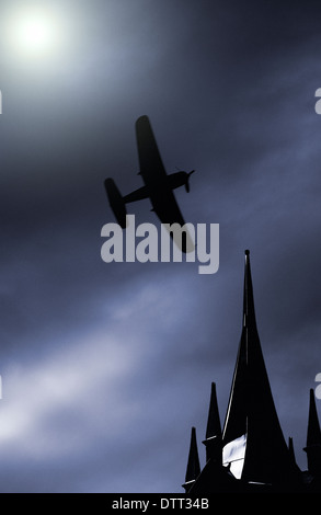 Alten Propeller-Jagdflugzeug fliegen auf einem mondbeschienenen Himmel über Gebäude auf dem Dach Stockfoto