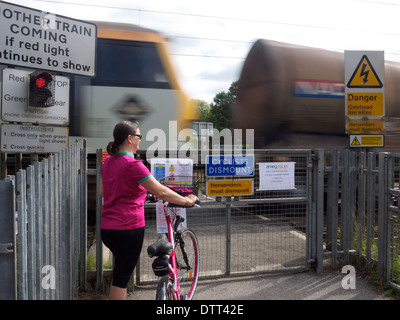 Radfahrer warten an einem Bahnübergang mit einem Zug vorbei Stockfoto