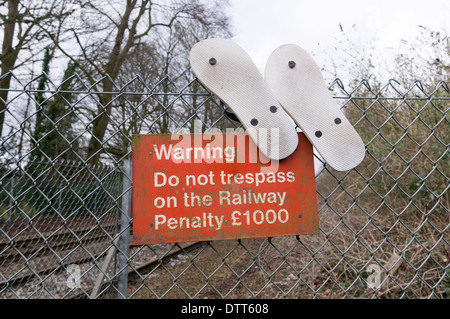 Flip Flop Schuhe hängen an einem Zaun oben rote Warnzeichen Stockfoto