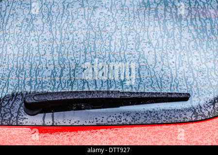 Detail der nassen roten Auto. Scheibenwischer und einem verregneten Fenster. Stockfoto