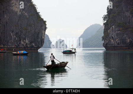 Zwei kleine Fischerboote jedes mit einem Mann auf, Manövrieren zwischen hohen Felsen in Ha Long Bay, Provinz Quang Ninh, Vietnam Stockfoto