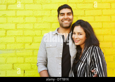 Indische paar umarmt vor gelben Mauer Stockfoto