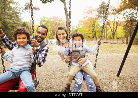 Familie sitzt auf Schaukeln im park Stockfoto