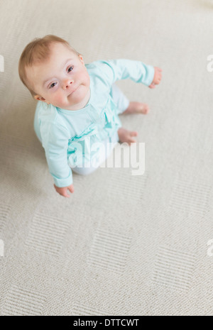 Kaukasische Mädchen mit Down-Syndrom am Boden Stockfoto