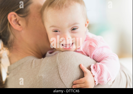 Kaukasische Mutter hält Babymädchen mit Down-Syndrom Stockfoto
