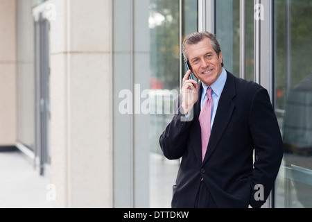 Kaukasische Geschäftsmann auf Handy außerhalb Gebäude Stockfoto