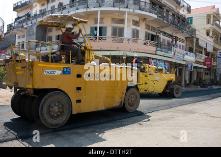 Männer fahren Rollen auf neue Pflaster auf eine Stadt Straße in Kampong Cham, Kambodscha. Stockfoto