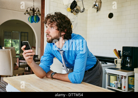 Kaukasische Geschäftsmann mit Handy in Küche Stockfoto