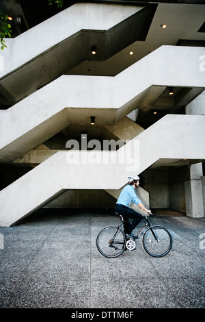 Kaukasische Geschäftsmann Reiten Fahrrad vor Bürogebäude Stockfoto