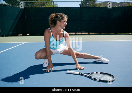 Kaukasische Frau stretching auf Tennisplatz Stockfoto