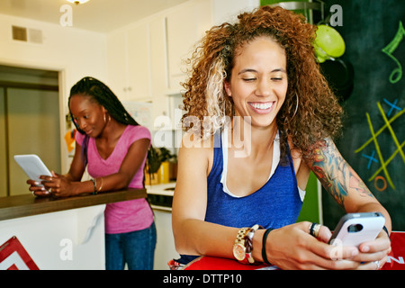 Frauen mit Technologie in Küche Stockfoto