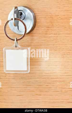Home-Taste mit leere Quadrat Schlüsselanhänger im Schloss der Holztür hautnah Stockfoto