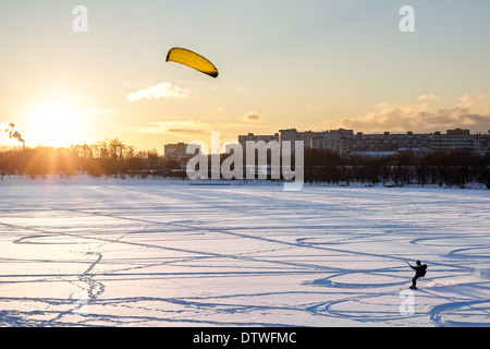 Snowkiten auf einem zugefrorenen Teich Hintergrund bei Sonnenuntergang Stockfoto