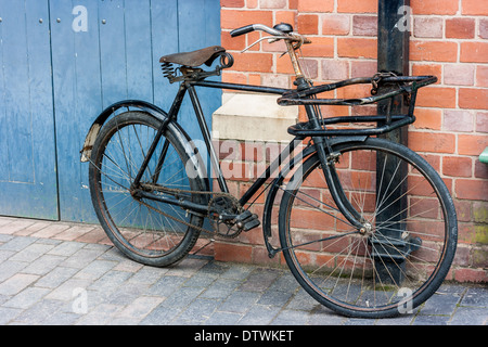 Alten Stil Fahrrad angekettet an ein Abflussrohr eine rote Wand bei Blists Hill viktorianischen Stadt Telford England gelehnt Stockfoto