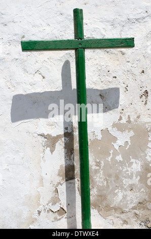 Grüne Holzkreuz gegen eine weiße Wand mit Schatten Stockfoto