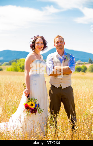 Braut und Bräutigam am Tag ihrer Hochzeit durch ein Feld in Oregon zusammen spazieren. Stockfoto