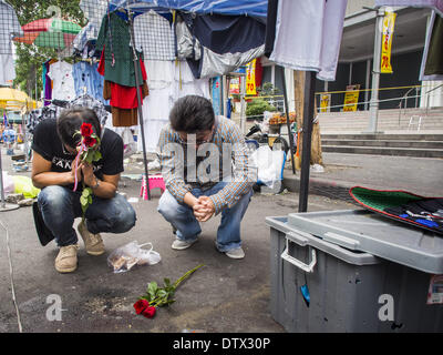 Bangkok, Thailand. 24. Februar 2014. Trauernde lassen Sie Blumen und beten an der Stelle, wo drei Menschen in einem Granatenanschlag auf Anti-Regierungs-Demonstranten im Stadtteil Ratchaprasong getötet wurden. Mindestens vier Personen, drei Kinder, starben in politischer Gewalt über das Wochenende. Eine in der Provinz Trat, in der Nähe der kambodschanischen Grenze und drei in Bangkok an der Ratchaprasong-Protest-Website. Am Standort Ratchaprasong wurde eine Granate in eine Menschenmenge, die Tötung eines Kindes und eines Erwachsenen gefeuert. Ein zweites Kind, verletzt in der Explosion starb über Nacht in einem Krankenhaus in Bangkok. (Kredit-Bild: © Jack Kurtz/ZUMAPRESS.c Stockfoto