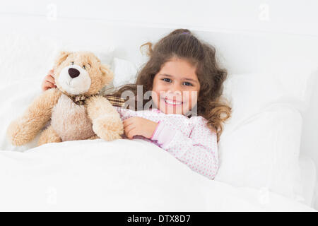 Kleines Mädchen mit Teddybär im Bett Stockfoto