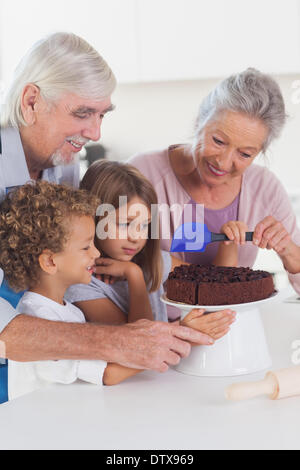 Kinder, die einen Kuchen in der Küche Puderzucker Stockfoto