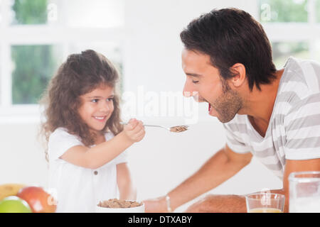 Kleines Mädchen, die Verfütterung von Getreide an Vater Stockfoto