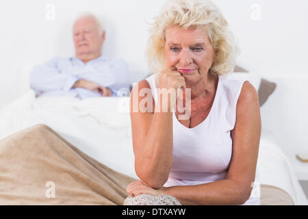 Entmutigt alte Frau sitzt auf dem Bett Stockfoto