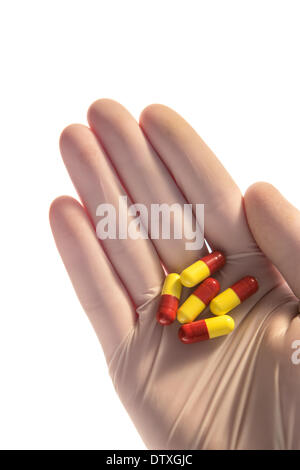 Behandschuhte Hand, die Tabletten in palm Stockfoto