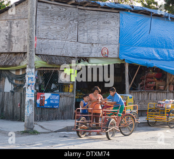 Familie Shopping-Trip. Eine Mutter und ihre beiden Söhne warten mit ihren Transporter Dreirad außerhalb ein Lebensmittelgeschäft in Tulum. Stockfoto