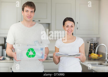 Paar Holding recycling bin und Zeitungen Stockfoto