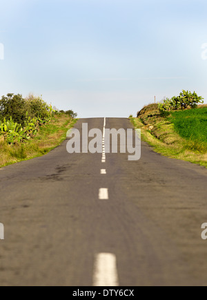 Lange Landstraße mit Markierungen auf blauen Himmelshintergrund Stockfoto