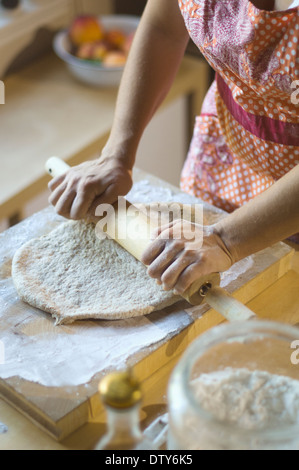 Gemischte Rassen Frau Rollen Teig auf Schneidebrett Stockfoto