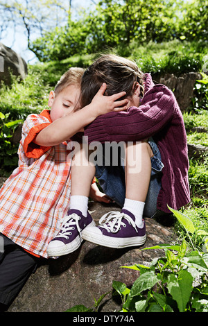 Gemischte Rassen junge tröstet Schwester im park Stockfoto