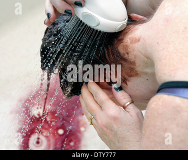 Frau, die Haare färben über eine Badewanne mit einem Duschkopf spülen Stockfoto