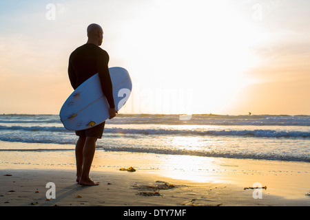 Gemischte Rassen Mann mit Surfbrett am Strand Stockfoto