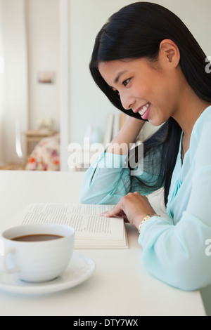 Chinesische Frau liest mit Tasse Kaffee Stockfoto