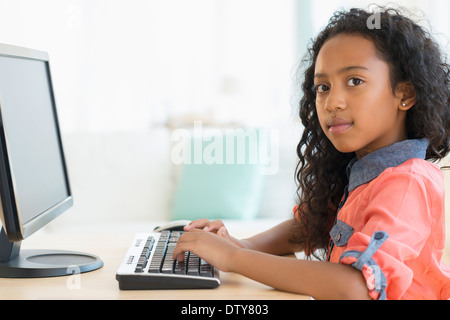 Gemischte Rassen Mädchen mit Computer am Schreibtisch Stockfoto