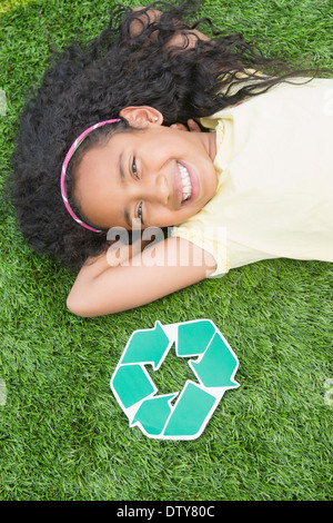 Gemischte Rassen Mädchen mit Recycling-Symbol im Rasen Stockfoto