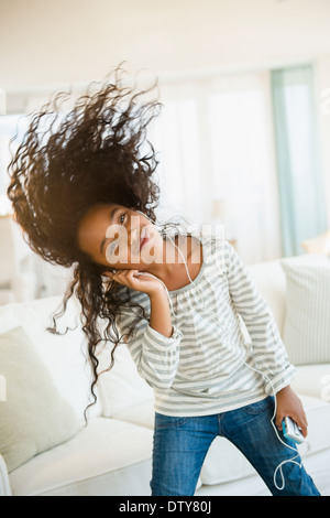 Gemischte Rassen Mädchen tanzen zu Kopfhörer im Wohnzimmer Stockfoto