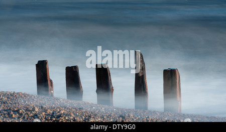 Das Meer wäscht auf den Resten eines längst vergangenen Steg entlang des Strandes von Winchelsea in East Sussex. UK Stockfoto